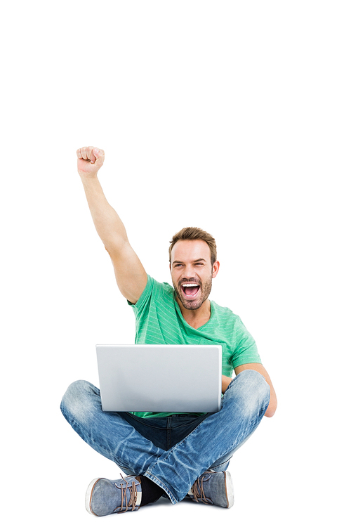 Happy young man raising his fist while using laptop on white background