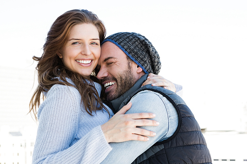 Happy couple cuddling each other and smiling outdoors