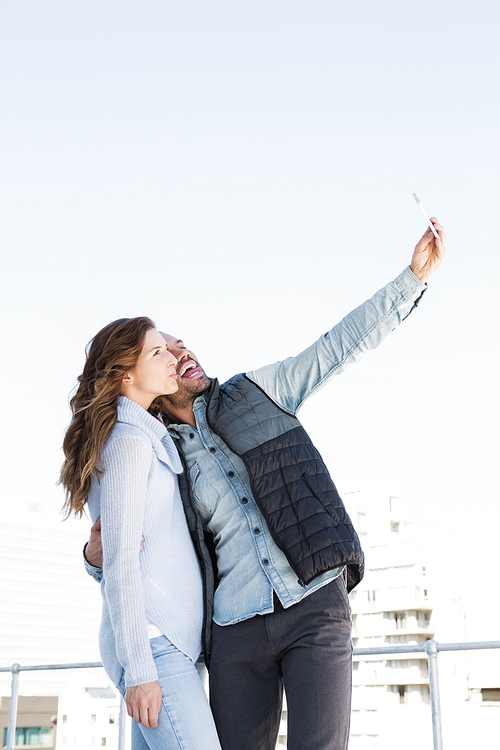 Young happy couple taking selfie on mobile phone outdoors