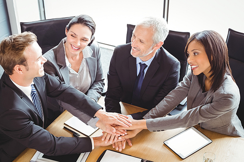 Businesspeople stacking hands in conference room in office