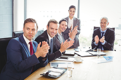 Businesspeople applauding in conference room during meeting