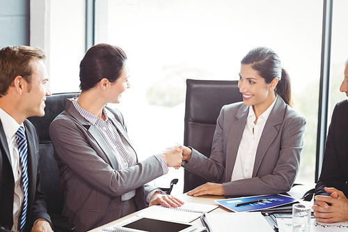 Businesspeople shaking hands in conference room during meeting