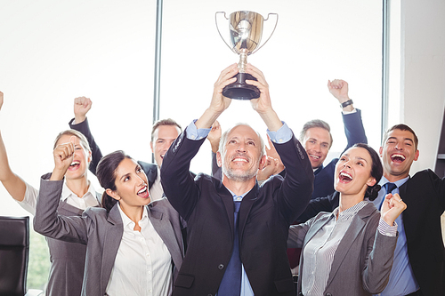 Portrait of winning business team with an executive holding a gold trophy