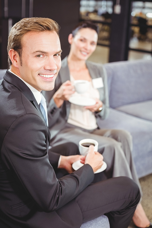 Portrait of businessman and businesswoman having tea during breaktime in office