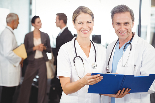 Portrait of happy doctors with clipboard in hospital