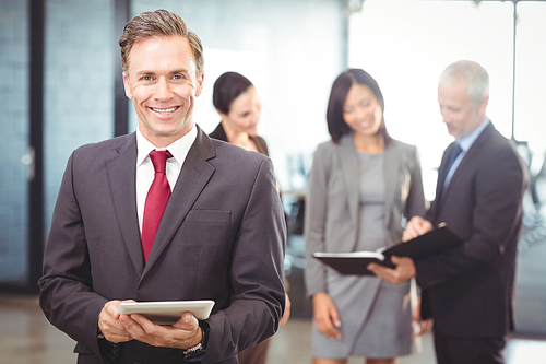 Portrait of happy businessman with digital tablet in office