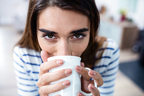 Portrait of young woman drinking coffee at home