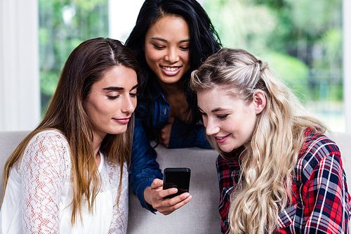 Close-up of young female friends looking in mobile phone at living room