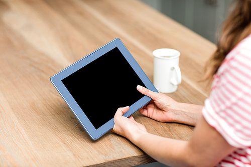 Cropped image of woman using digital tablet by table at home