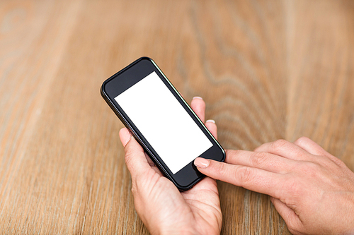 Cropped hand of woman using smart phone by table at home