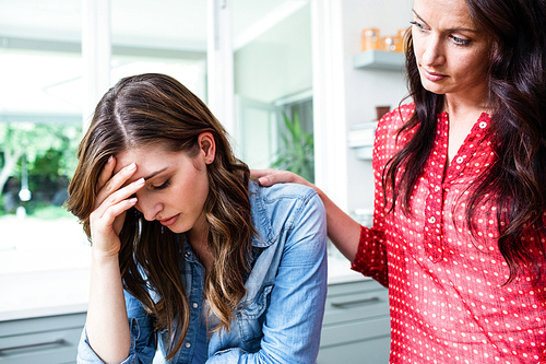 Worried young woman with friend at home
