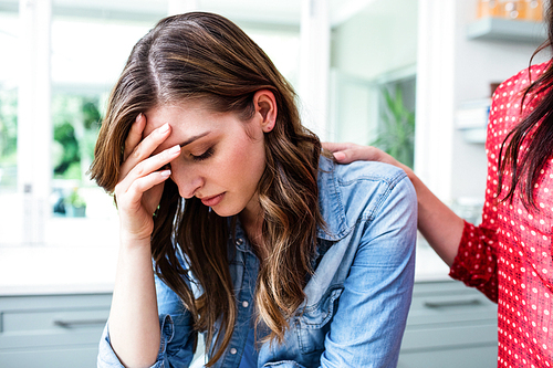 Sad young woman with friend at home