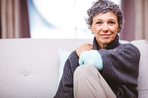 Portrait of smiling mature woman sitting on sofa at home