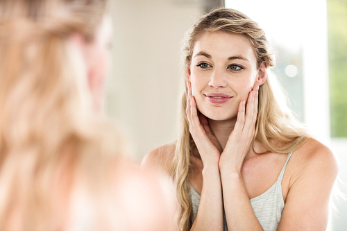 Happy young woman looking in mirror at home