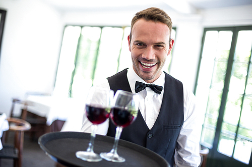 Waiter holding tray with red wine in a commercial kitchen