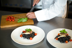 Handsome chef slicing garnish in a commercial kitchen