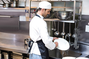 Handsome employee doing dishes in commercial kitchen