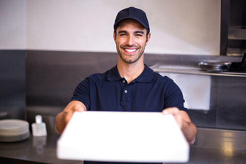 Pizza delivery man showing box in commercial kitchen