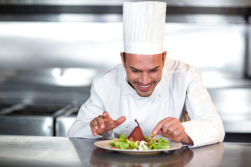 Happy chef garnishing food in a commercial kitchen