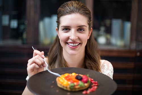 Portrait of happy woman with tart in restaurant