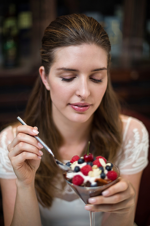 Happy woman enjoying desert with fruits in restaurant