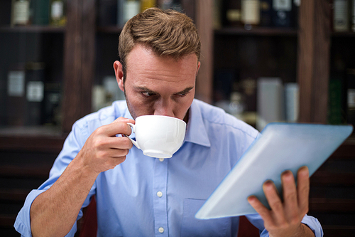 Businessman using digital tablet while having coffee at restaurant