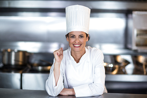 Portrait of smiling female chef standing in commercial kitchen