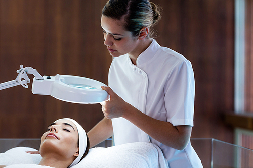 Masseuse looking at woman face at spa