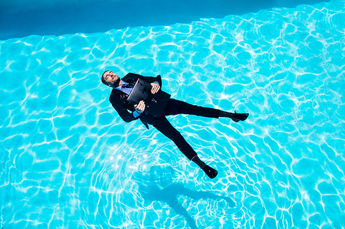 Dressed businessman in swimming pool on a sunny day