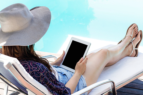 Woman using her tablet by swimming pool