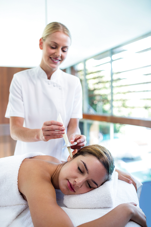 Woman receiving ear candle treatment at spa