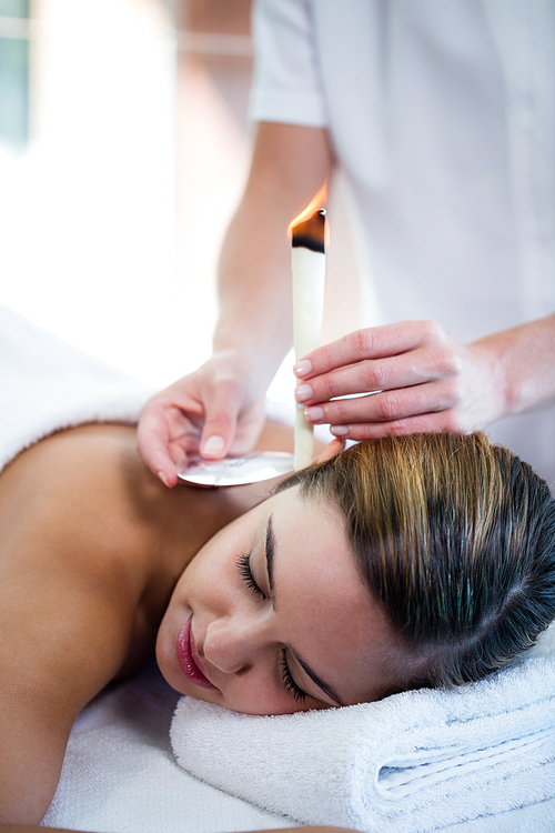 Woman receiving ear candle treatment at spa