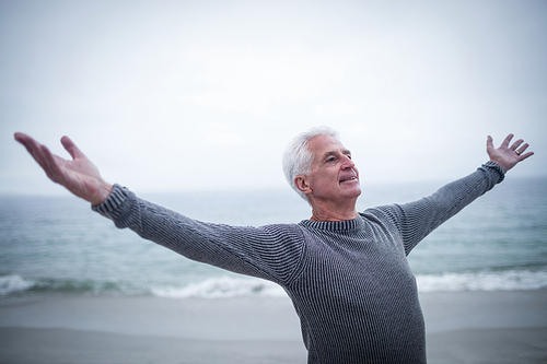 Senior man with arms outstretched on the beach