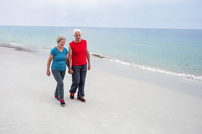 Senior couple holding hands and walking on the beach happily