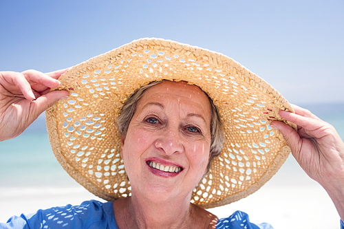 Close-up of happy senior woman in beach hat and smiling on the beach