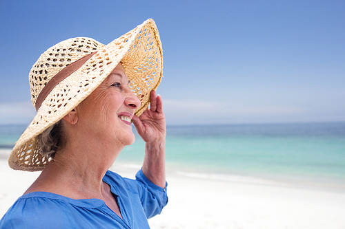 Close-up of happy senior woman in beach hat and smiling on the beach