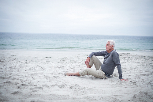 Thoughtful retired man sitting on the beach on holidays
