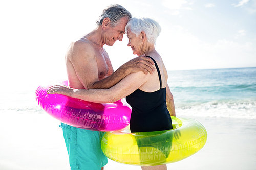 Senior couple in inflatable ring embracing each other on beach