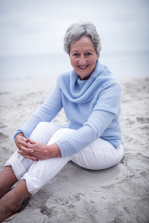 Portrait of senior woman sitting on beach on a sunny day