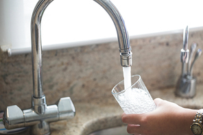 Close-up of woman washing a glass in kitchen sink at home