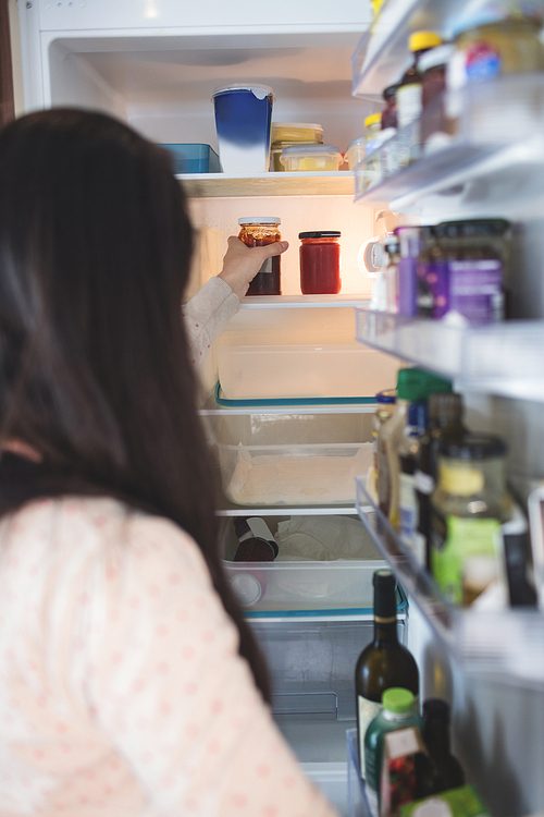 Woman checking food in refrigerator at home
