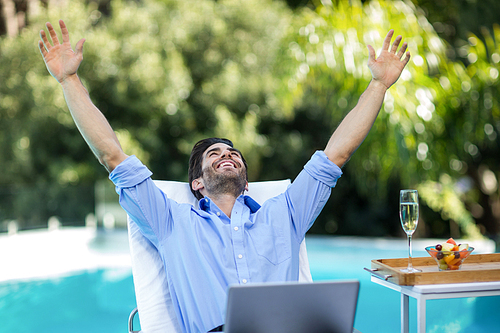 Excited man using a laptop near the pool