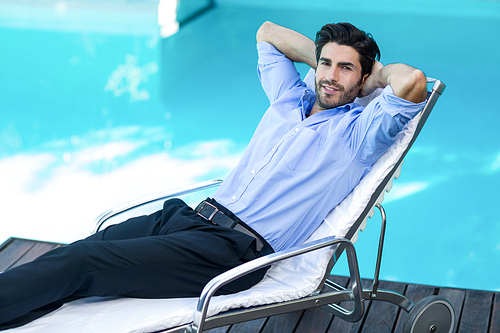 Portrait of smart man relaxing on sunlounger near pool