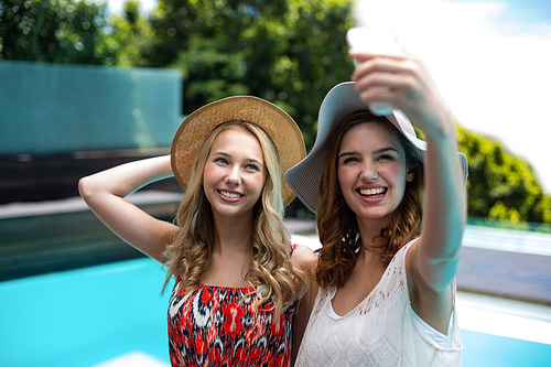 Beautiful women taking a selfie by swimming pool on a sunny day