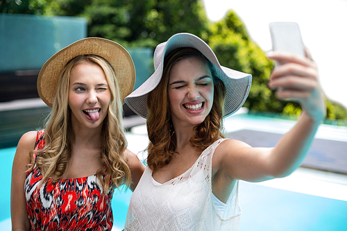 Beautiful women taking a selfie by swimming pool on a sunny day