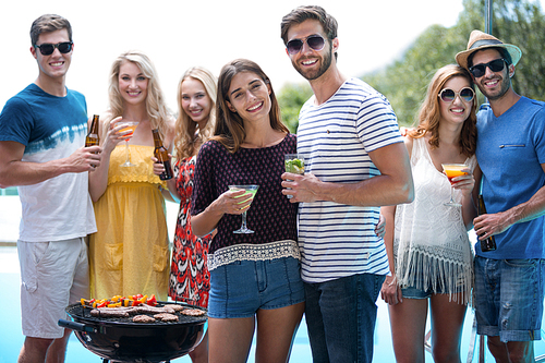 Group of friends holding a glass of cocktail and beer on a sunny day