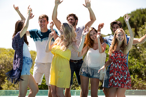 Happy friends dancing near the swimming pool on a sunny day