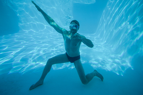 Man posing underwater in swimming pool at resort
