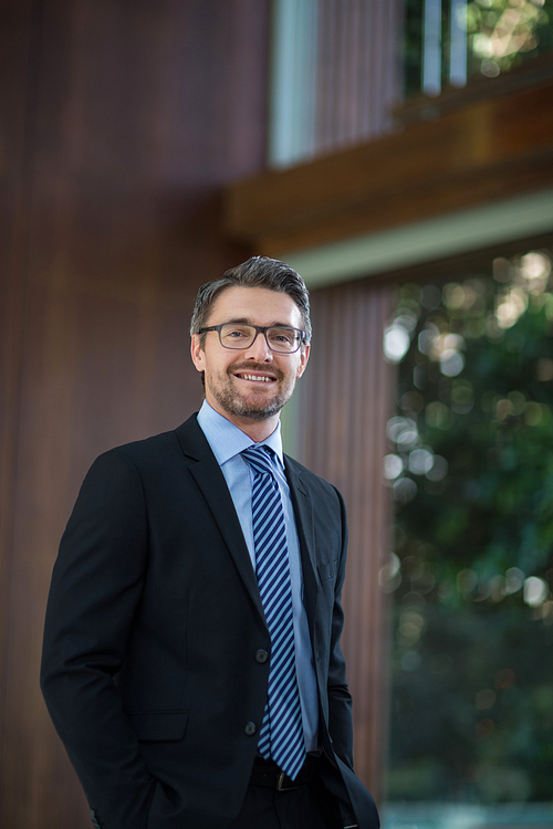 Portrait of happy businessman standing in resort