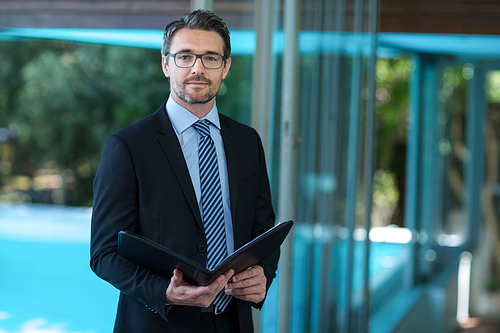 Portrait of businessman in suit holding folder at resort